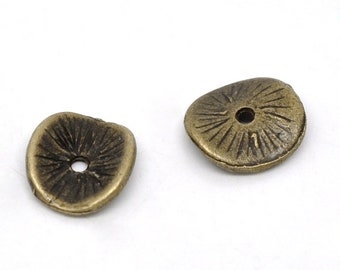 May include: Two antique bronze-colored metal beads. Each bead is irregularly shaped with a central hole and a textured, sunburst-like pattern radiating from the center. The beads are likely for jewelry making or crafts.