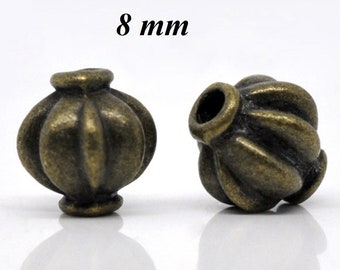 May include: Two antique bronze-colored beads, each with a unique, ribbed design. The beads are approximately 8 mm in diameter and have a hole running through the center. The beads are likely used for jewelry making or other crafts.
