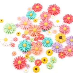 May include: Assortment of colorful plastic flower embellishments in various pastel shades, including pink, blue, green, and yellow. The flowers are all different sizes and shapes, with some having a more realistic look and others being more stylized.