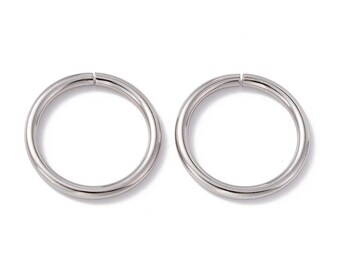 May include: Two silver-colored, circular hoop earrings. Each earring is a complete circle with a small gap at the top. The earrings are made of a shiny, metallic material and are set against a white background.