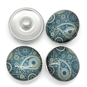 May include: Four circular snap buttons featuring a dark blue and teal paisley pattern with intricate floral and circular motifs. Three buttons display the patterned top, while one button shows the silver-toned metal underside with a central stud.