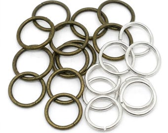May include: A collection of circular metal jump rings in two distinct finishes. Several rings feature an antique bronze tone with a matte texture, while others are finished in a bright, polished silver tone. Each ring has a single split opening.