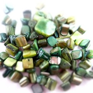 May include: A collection of green and gold iridescent shell beads. The beads are various shapes and sizes, with some being square, rectangular, and triangular.