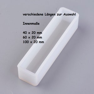 Pode incluir: Molde de silicone branco para fundição de resina. O molde é retangular com uma abertura retangular. O molde está disponível em três tamanhos: 40 x 20 mm, 60 x 20 mm e 100 x 20 mm.