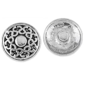 May include: Two silver-colored snap buttons. One button features an ornate, raised floral design around a central circle. The other button shows the back with a central post. These buttons are likely used for jewelry or clothing.