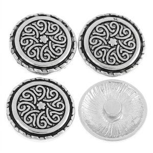 May include: Four round silver-toned metal buttons. Three buttons display a raised, intricate swirling pattern with a small flower at the centre and a rope-textured border. One button is shown from the back, revealing a smooth, flat circular attachment.