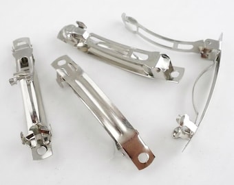 May include: Four silver-toned metal hair barrettes with a spring-loaded clasp mechanism. Each barrette features a smooth, curved rectangular body with a small circular hole at one end and a hinged tension bar designed to secure hair in place.