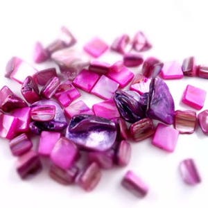 May include: A collection of pink and purple iridescent shell tiles. The tiles are various shapes and sizes, including squares and rectangles.