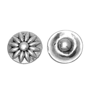 Könnte beinhalten: Zwei silberfarbene Metallknöpfe. Ein Knopf hat ein erhabenes Blumendesign mit einer zentralen Kugel und blütenblattartigen Formen. Der andere Knopf hat eine glatte, abgerundete Oberfläche mit einer zentralen erhabenen Kugel. Beide Knöpfe sind kreisförmig.