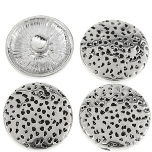 May include: Four circular silver-toned metal buttons. Three buttons display a textured, pitted surface pattern on the front, while one button is flipped over to reveal a smooth, radial-lined underside with a central metal shank attachment point.