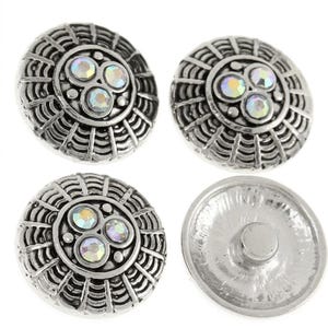 May include: Four round silver-toned metal snap buttons. Three buttons feature a textured web-like pattern with a central cluster of three iridescent, multi-colored rhinestones. The fourth button shows the smooth, plain silver-toned metal underside.