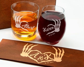 May include: Two engraved wine glasses with a skeleton hand design and the names Albert and Karen, along with the date 10 30 2023. The glasses are in a wooden box with a matching engraved wooden coaster.