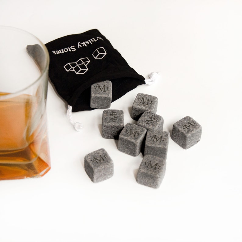 May include: A black velvet bag with the words "Whiskey Stones" printed on it, containing eight gray square whiskey stones with the letter "M" engraved on each.