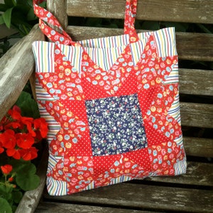 May include: A red, white and blue patchwork tote bag with a star design. The bag has a floral print and is made of fabric.