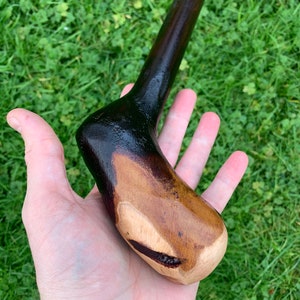 May include: A wooden walking stick with a dark brown finish and a natural wood handle. The handle is shaped to fit comfortably in the hand.