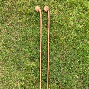 May include: Two wooden walking sticks with rounded tops. The sticks are brown and have a natural wood finish.