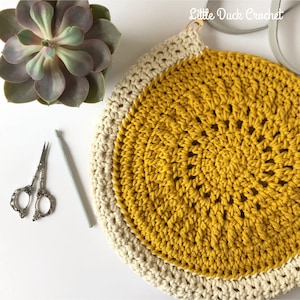 Peut inclure: Un sac en crochet avec un centre jaune et une bordure blanche. Le sac a une anse et est fait avec un fil &eacute;pais.