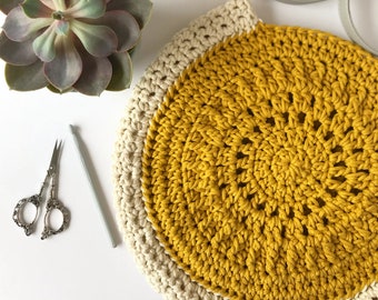 May include: A crocheted bag with a yellow center and a white border. The bag has a handle and is made with a thick yarn.