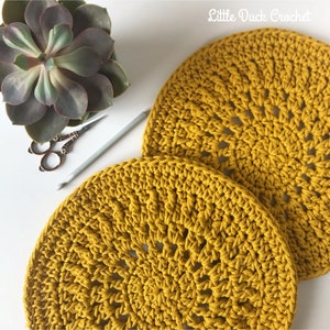Peut inclure: Deux sets de table ronds en crochet de couleur jaune moutarde. Les sets de table sont r&eacute;alis&eacute;s avec un motif de point simple et ont une surface l&eacute;g&egrave;rement textur&eacute;e.