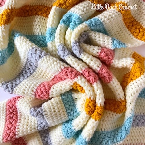 May include: A crocheted baby blanket with stripes of white, grey, pink, blue and yellow yarn. The blanket is folded and textured with a popcorn stitch.
