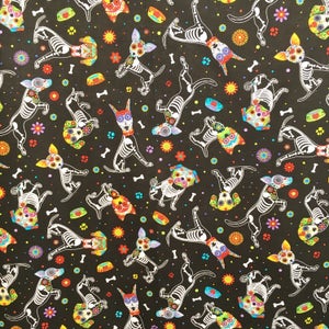 May include: Black fabric with a repeating pattern of white skeleton dogs with colorful flowers and skulls. The dogs are in various poses, some are standing, some are sitting, and some are running.