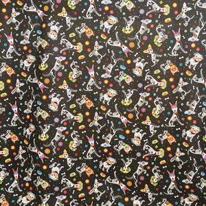 May include: Black fabric with a repeating pattern of white skeleton dogs wearing colorful flower crowns. The dogs are in various poses and are surrounded by small colorful flowers and bones.