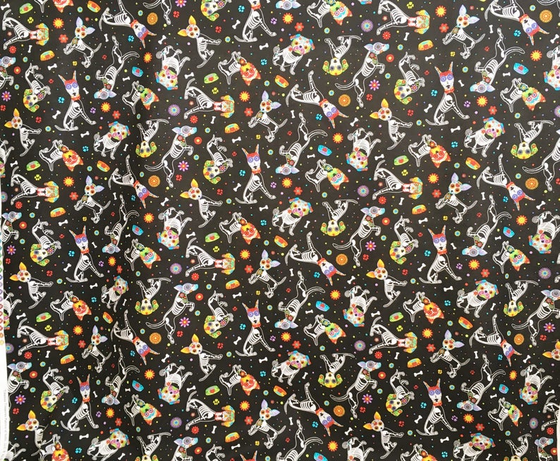 May include: Black fabric with a repeating pattern of white skeleton dogs wearing colorful flower crowns. The dogs are in various poses and are surrounded by small colorful flowers and bones.