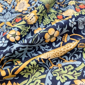 May include: Close-up of navy blue fabric with a floral pattern. The design features yellow flowers, green leaves, and light blue accents. A stylized lizard with yellow and brown markings is also visible.