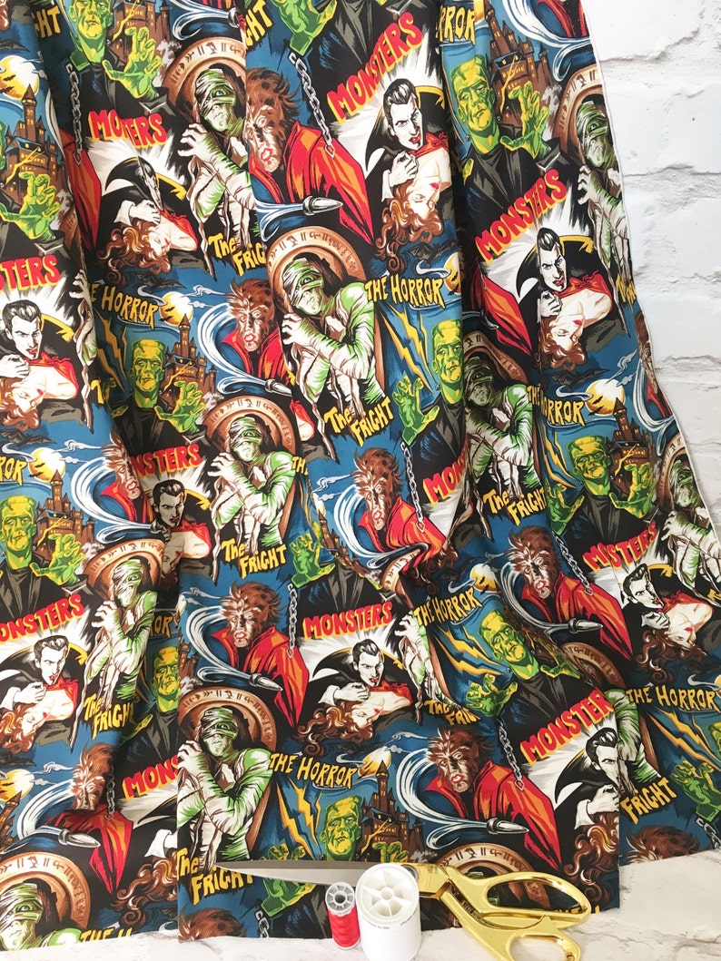 May include: A blue and black fabric with a repeating pattern of vintage horror movie posters featuring classic monsters like Dracula, Frankenstein, the Mummy, and the Wolfman. The posters have text that reads "Monsters", "The Horror", and "The Fright".
