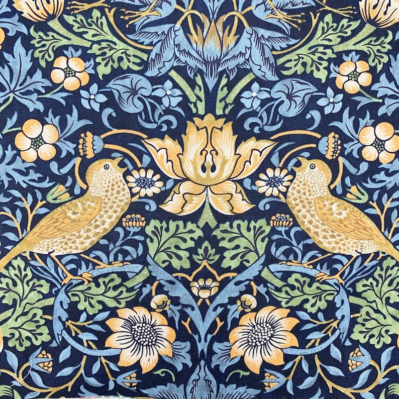 May include: Close-up of a fabric with a repeating pattern of birds, flowers, and foliage. The design features tan birds, yellow flowers, and green leaves against a navy blue background. The floral pattern includes stylized blooms and intricate details.