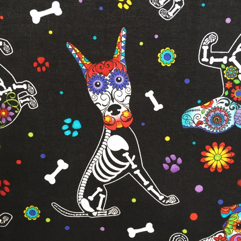 May include: A black fabric with a repeating pattern of colorful, sugar skull-decorated dog skeletons. The dogs are in various poses, including sitting, standing, and running. The fabric also features small, colorful flowers and paw prints.