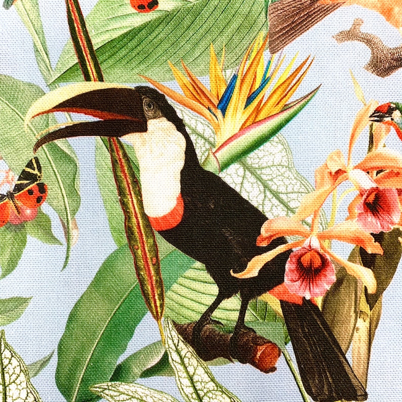 Puede incluir: Un tuc&aacute;n con cuerpo negro y blanco y un gran pico naranja est&aacute; posado en una rama con hojas verdes. El tuc&aacute;n est&aacute; rodeado de orqu&iacute;deas rosas y amarillas y otras plantas tropicales.