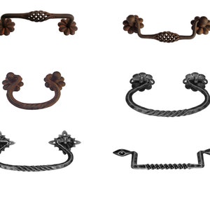 Könnte beinhalten: Eine Sammlung von acht dekorativen Schrankgriffen mit rustikalem, antikem Finish. Die Griffe haben verschiedene Designs, darunter florale, geschwungene und gedrehte Drahtformen.