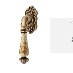 May include: Antique brass cabinet knob with a decorative floral design and a ceramic handle. The knob measures 1.4 inches in width, 6.4 inches in height, and 2.7 inches in depth. COD: 1546 DK