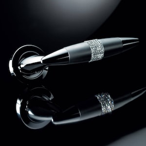 Könnte beinhalten: Ein silberner Türgriff mit einem Band aus klaren Kristallen. Der Griff ist gebogen und hat eine runde Basis.