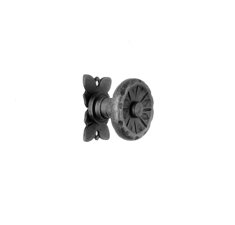 May include: A black metal door knob with a decorative, circular design. The knob has a square backplate with a floral design.