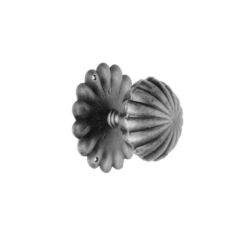 May include: A black metal door knob with a decorative, scalloped design. The knob has a round, fluted shape and a flat, decorative backplate.
