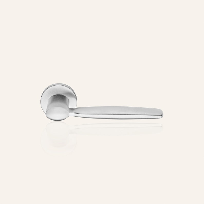 May include: A silver door handle with a round base and a long, straight lever.