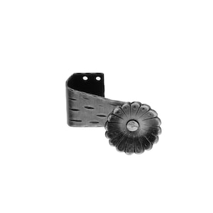 Könnte beinhalten: Eine schwarze Metall-Vorhangstangenhalterung mit einem dekorativen, blumenförmigen Knopf. Die Halterung hat eine strukturierte Oberfläche und zwei kleine Löcher.