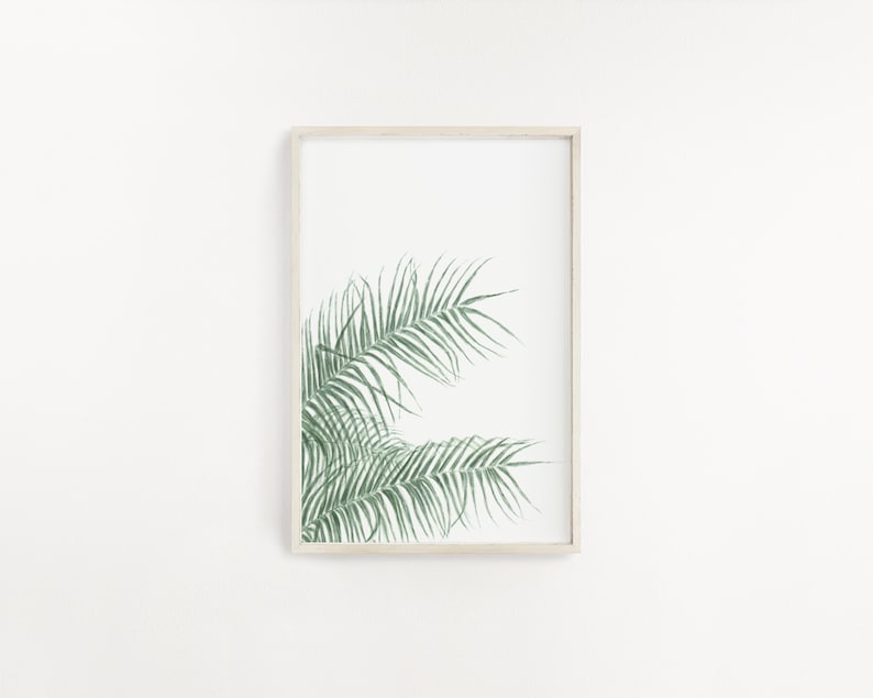 以下が含まれることがあります： 白い背景に緑色のヤシの葉が描かれた額装されたプリント