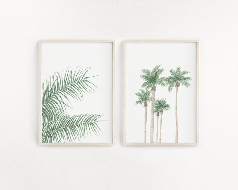 以下が含まれることがあります： 植物のイラストが描かれた額装されたプリントが2枚。左側のプリントは緑色のヤシの葉のクローズアップ。右側のプリントは緑色の葉を持つヤシの木が5本並んでいる。