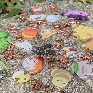 May include: A collection of colorful character charms with gold star-shaped keychains. The charms are made of clear acrylic and feature various cartoon characters.