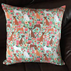 Peut inclure: Un oreiller turquoise avec un motif r&eacute;p&eacute;t&eacute; de boxers bruns et blancs et de fleurs roses.