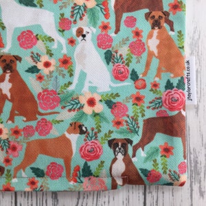 Peut inclure: Un tissu turquoise avec un motif r&eacute;p&eacute;t&eacute; de chiens boxers bruns et blancs et de fleurs roses, rouges et orange. Le tissu a une &eacute;tiquette blanche avec le texte "jtaylorcrafts.co.uk".
