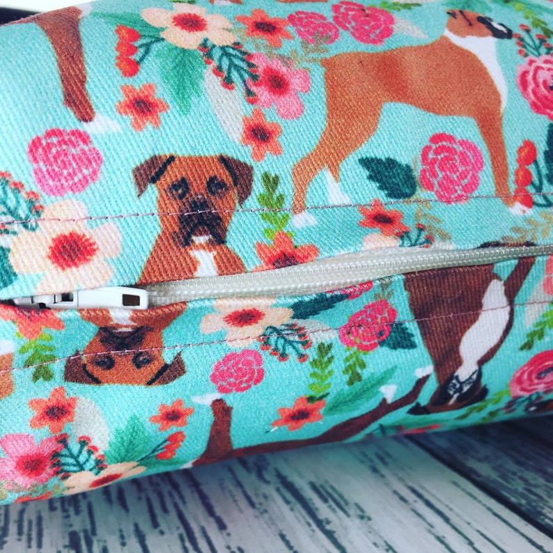 Peut inclure: Un oreiller bleu turquoise avec une fermeture &eacute;clair. L'oreiller pr&eacute;sente un motif r&eacute;p&eacute;t&eacute; de chiens boxers bruns et de fleurs roses, rouges et vertes.