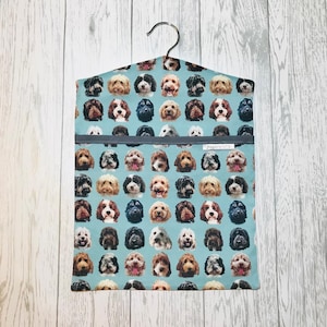 May include: A blue laundry bag with a hanger, featuring a repeating pattern of various dog breeds. The bag has a gray zipper and the text "Staynercrafts" is printed on the front.