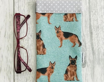 Peut inclure: Un étui à lunettes en tissu bleu clair avec une bordure à pois blancs. L'étui présente un motif répété de chiens bergers allemands. L'étui porte une étiquette blanche avec le texte "Jhoylecrafts".