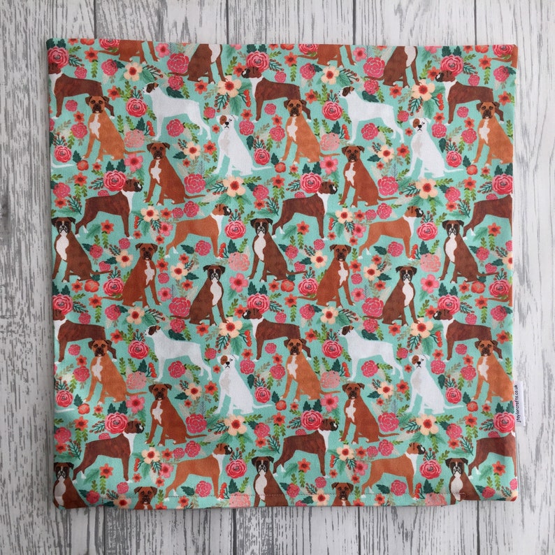 Peut inclure: Un tissu turquoise avec un motif r&eacute;p&eacute;t&eacute; de chiens boxers bruns et blancs et de fleurs roses, blanches et vertes.