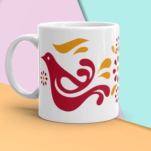 Puede incluir: Taza de cerámica blanca con un diseño de pájaro rojo estilizado y detalles florales amarillos.