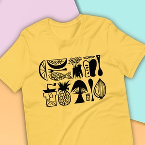 May include: A yellow t-shirt featuring a black graphic design of assorted fruits, vegetables, and kitchen utensils. The design includes a pineapple, watermelon, mushroom, fish, and a pepper shaker.